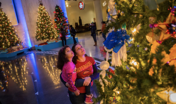 Mother and daughter gaze at decorated tree from Museum of Science and Industry's Christmas Around the World and Holiday of Lights Exhibit