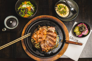 Asian cuisine from Gaijin is served at a wooden table with chopsticks