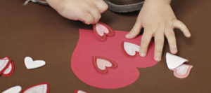 Child's hands apply hearts onto a homemade valentine