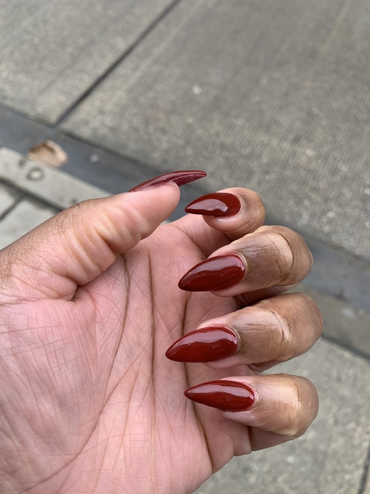 a hand showing off a manicure, deep red almond-shaped nails; hyde park chicago nail salon